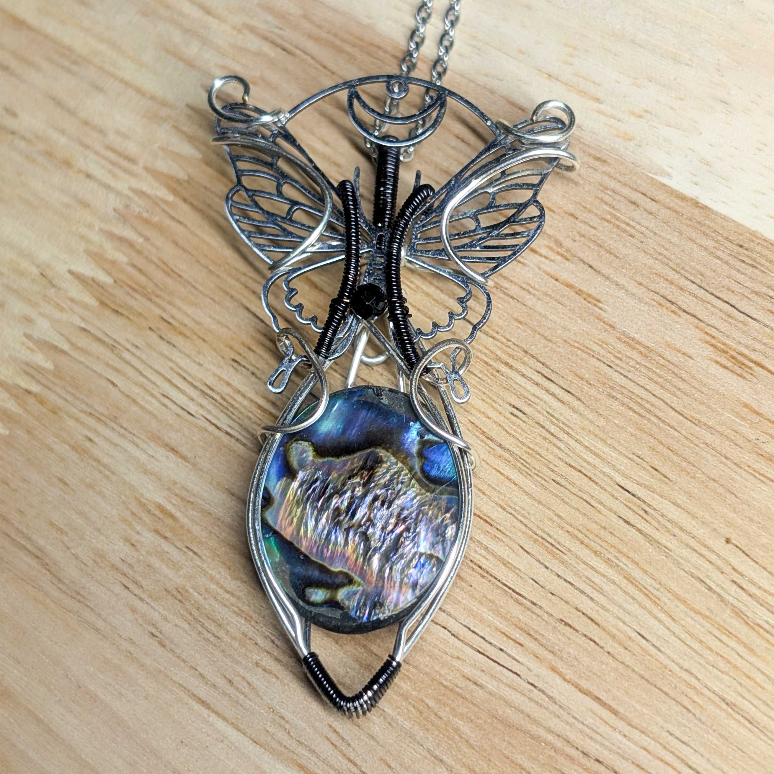 Pendentif nacre Abalone irisée avec tressage cuivre patiné sur fond blanc