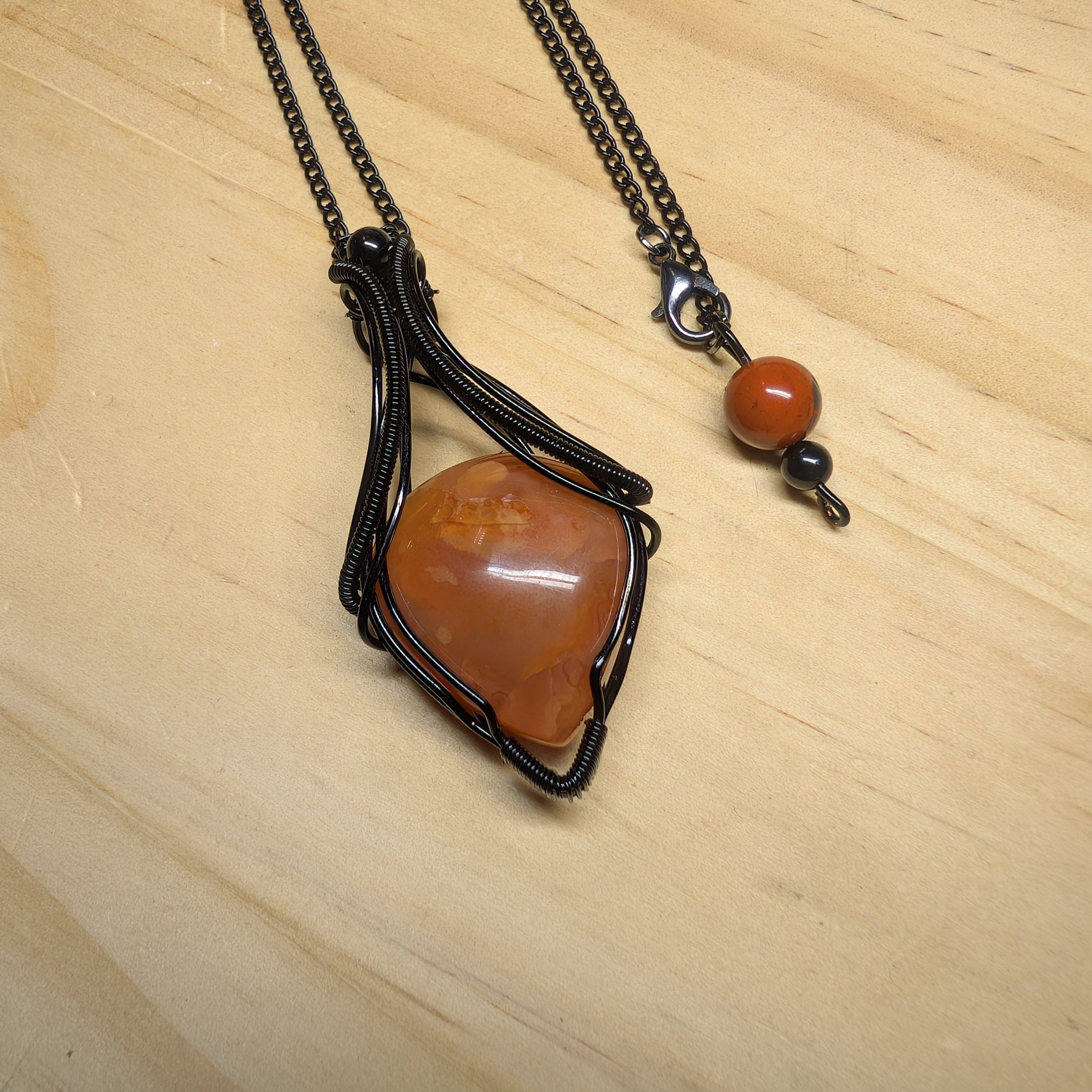 Pendentif artisanal en cornaline naturelle orangée serti dans cuivre patiné full black anti-ternissement, création unique fait main